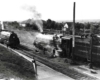 Men work on a steam locomotive while a second approaches