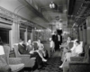 A black and white photo of passengers sitting in a lounge car