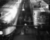A black and white overhead shot of passengers walking to a train