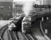 A black and white photo of two locomotives turning a corner at the same time