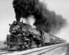 A black and white photo of a train with black smoke coming out of its chimney