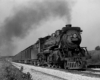 A black and white photo of a locomotive with smoke coming out of its chimney