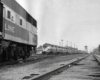 a diesel passenger train rolling up to an E unit in the foreground