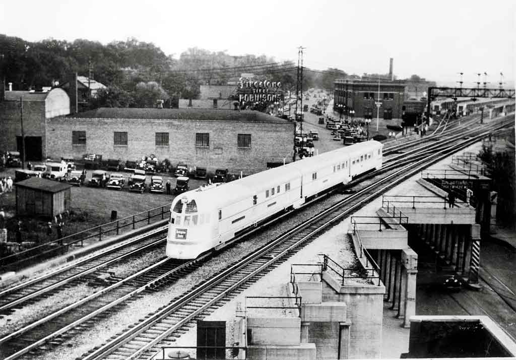 A black and white photo of a locomotive passing over a bridge