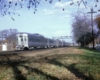 A silver train passing underneath a stop light