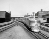 A black and white close up photo of a train traveling through a station