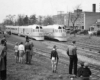 A black and white photo of a group of people watching two passenger trains go by