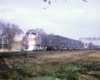 A silver train passing underneath a stop light