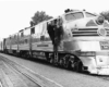 A black and white photo of a conductor climbing up a ladder into the train