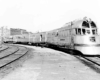 A black and white train with people on it turning a corner