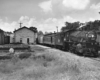 A black and white photo of a train traveling past a building