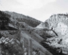 A black and white photo of a train traveling through a mountian