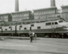 A black and white photo of a couple people standing outside a locomotive