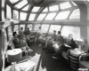 A black and white photo of people sitting inside a train with a lot of windows