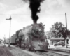 A black and white photo of a locomotive with black smoke coming out of its chimney