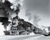 A close up black and white photo of a locomotive with smoke coming out of its chimney