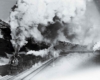 A black and white photo of a train with big white smoke coming out of its chimney