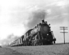 Steam locomotive with four passenger cars at speed