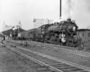 A black and white photo of two trains passing through a station