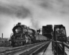 A black and white photo of a train exiting a bridge