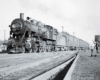 A black and white photo of a train passing by someone standing outside