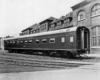 A black and white photo of a sleeping car parked outside a building