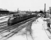 A black and white photo of a train departing a station