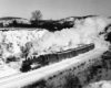 a steam passenger train rounding a curve on a winter day