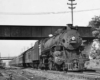 A black and white photo of a training moving under a bridge