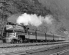 A black and white photo of a train with white smoke coming out of its chimney