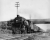 A black and white locomotive passing underneath a bridge