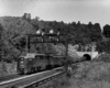 A black and white photo of a train leaving a tunnel