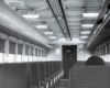 A black and white photo of the back of a passenger's head while sitting inside a train