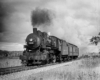 A black and white photo of a locomotive with black smoke coming out of a chimney