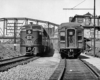 A black and white photo of two trains passing eachother on the tracks