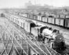 a steam engine pulling passenger cars in a rail yard