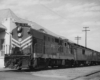 a diesel and passenger cars by a passenger depot