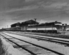 a diesel pulling passenger cars past a depot