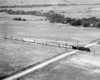 A distant, overhead shot, of a train passing through a rural area