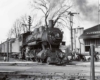 a steam engine passenger train sitting next to a train station