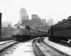 a passenger train passes another passenger train with Chicago buildings in the background
