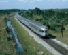 A streamlined silver-colored passenger train as seen above and from the rear.