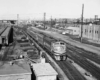 a diesel passenger train rolling by some buildings