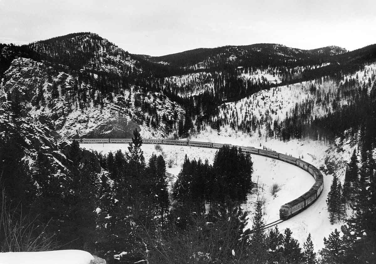 a diesel passenger train rounding a curve surrounded by woods