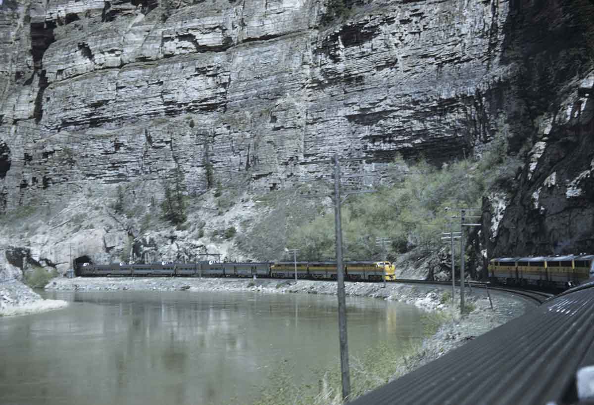 two diesel passenger trains about to pass each other in a canyon
