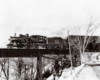 A black and white photo of a train crossing a bridge