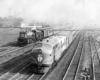 A black and white photo of two trains coming down the tracks