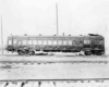 A black and white photo of a gas-electric car sitting on the tracks