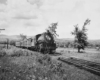 A black and white photo of a locomotive moving on the tracks