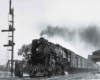 A black and white photo of a train exiting a tunnel